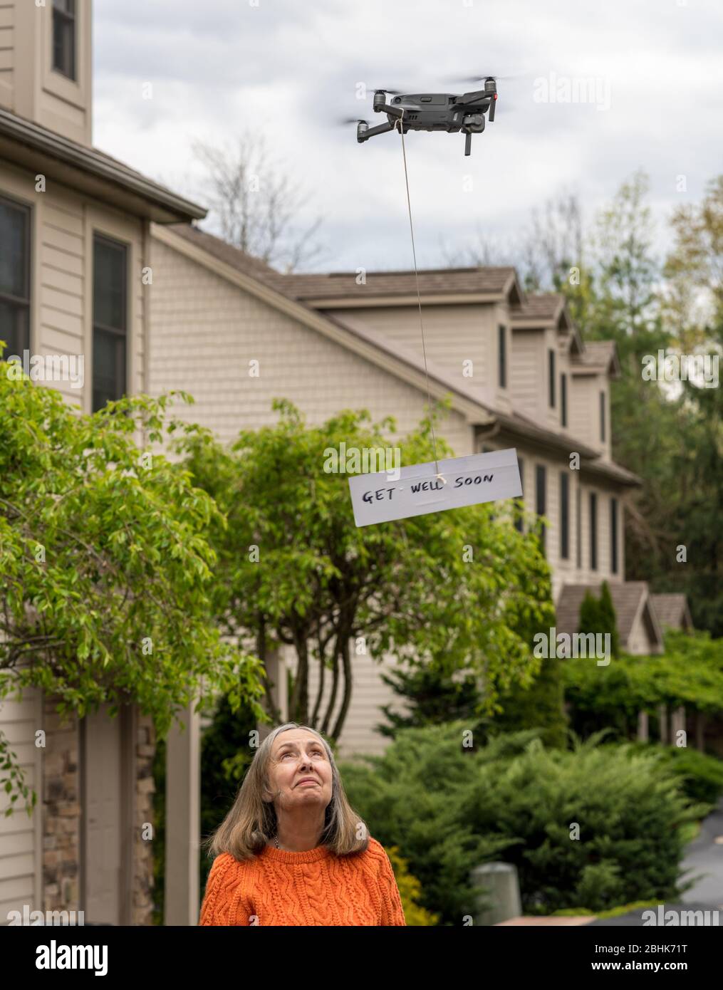 Flying drone delivering a get well soon message touch free to a quarantineed grandmother during coronavirus epidemic Stock Photo