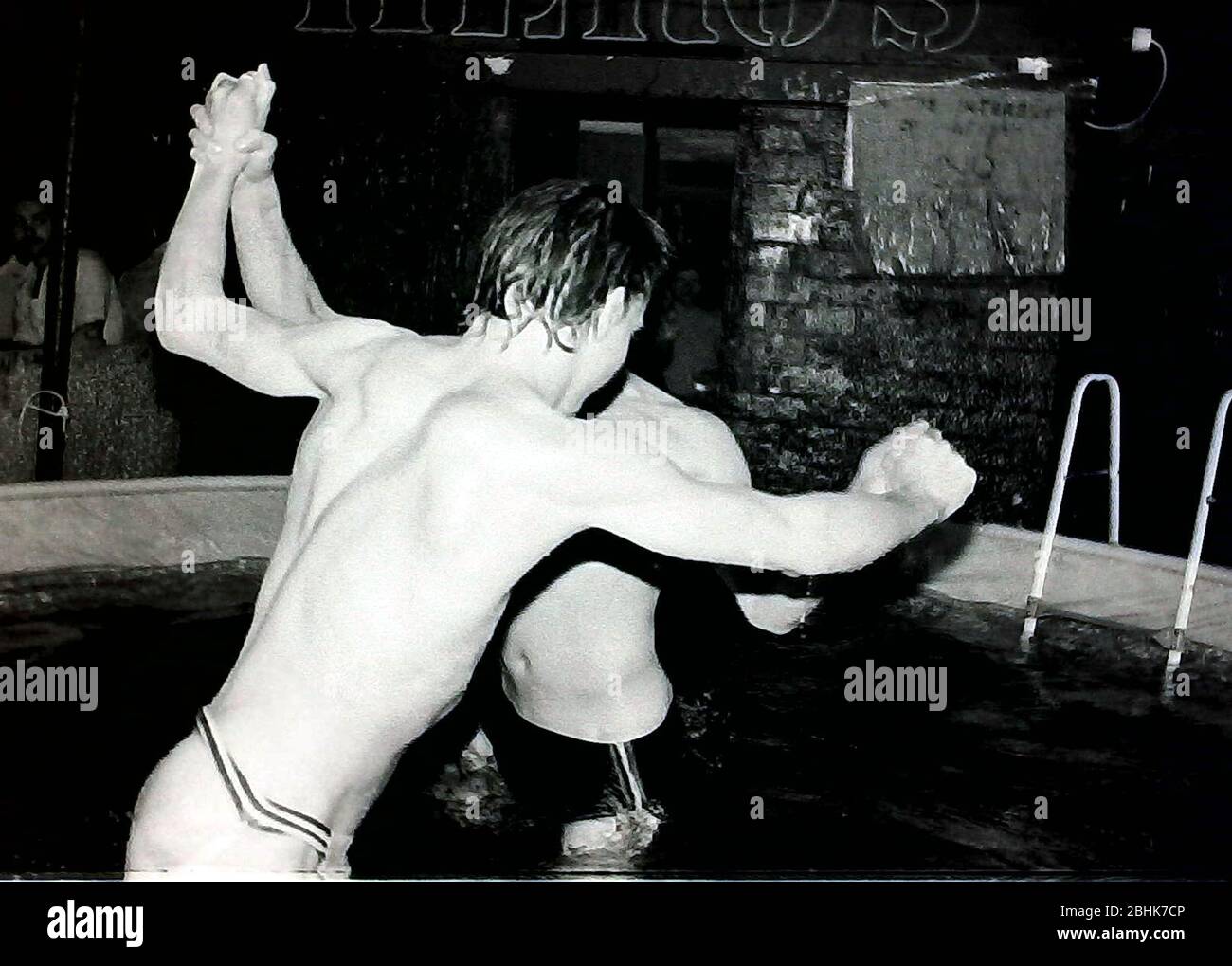 Two young men wrestling in a temporary swimming pool in Hero's club in Manchester, England, United Kingdom, a popular club for gay male customers, in April 1984. Daily life in the night life of Manchester's gay clubs and bars in the 1980's. Stock Photo