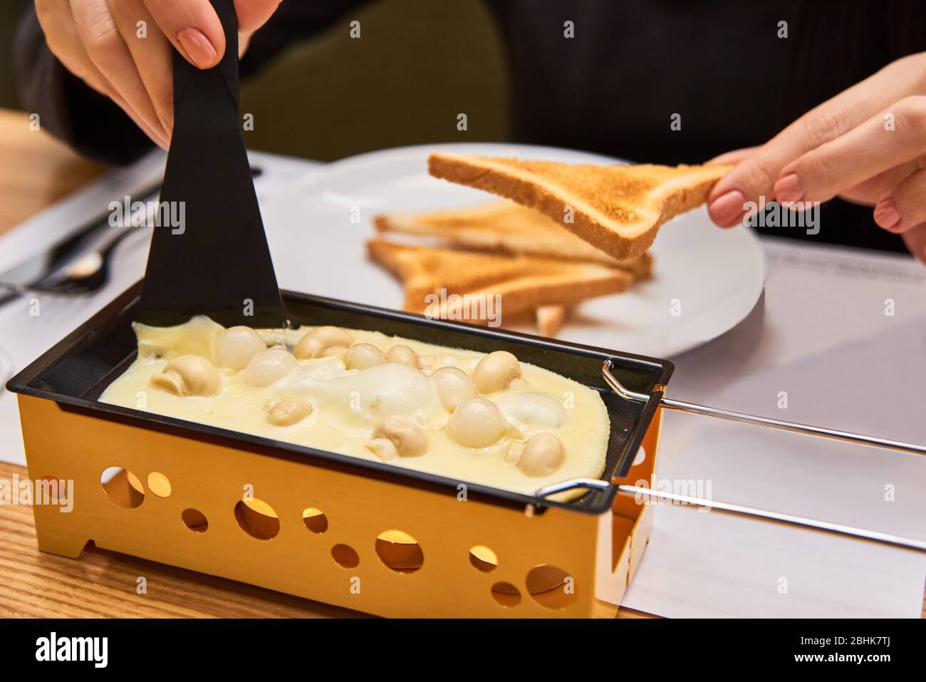 swiss food. cheese raclette with mushrooms on coupelles - special small skillet for a raclette Stock Photo