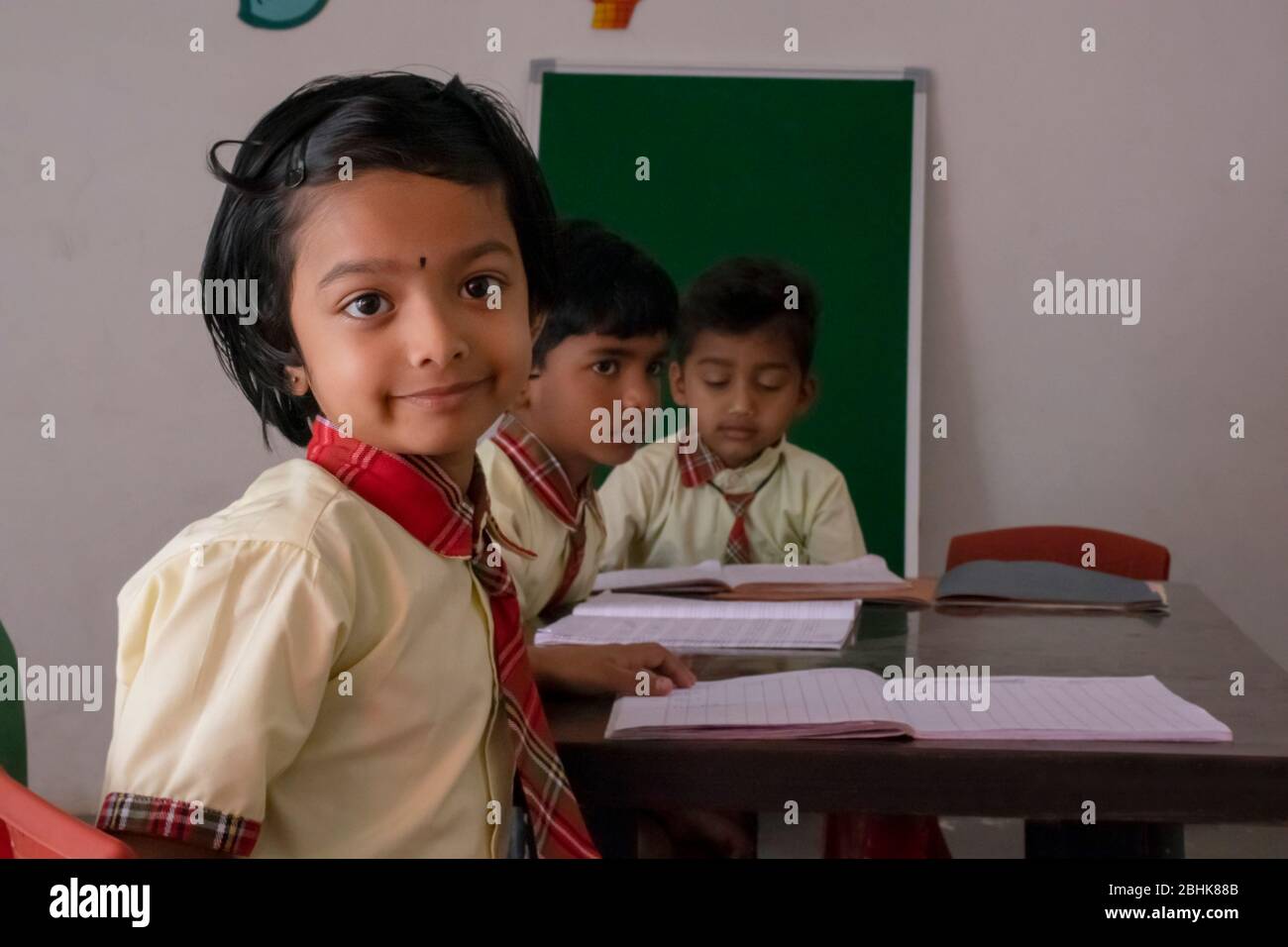 Happy Young primary or elementary school children sitting at their desks in a classroom, India Stock Photo