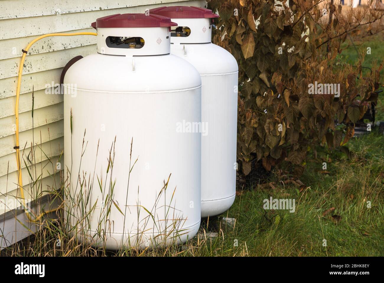 Propane cylinders against the external wooden wall of a house Stock Photo