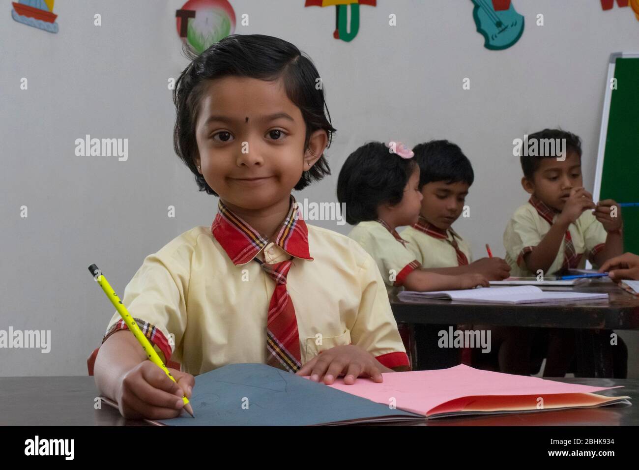 Happy Young primary or elementary school children sitting at their desks in a classroom, India Stock Photo