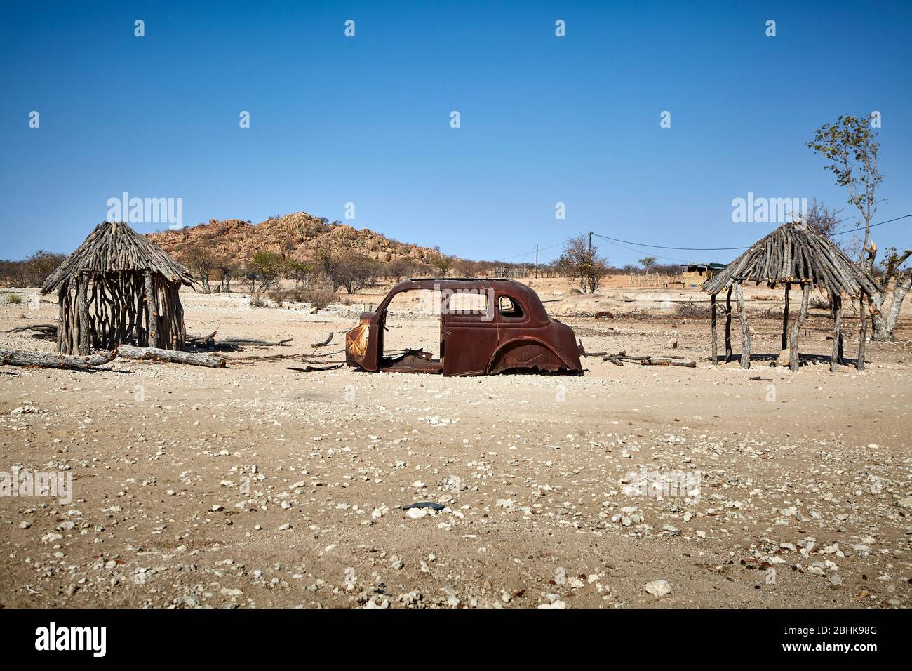 Nice arrangement: An end-of-life vehicle framed by two huts. Stock Photo