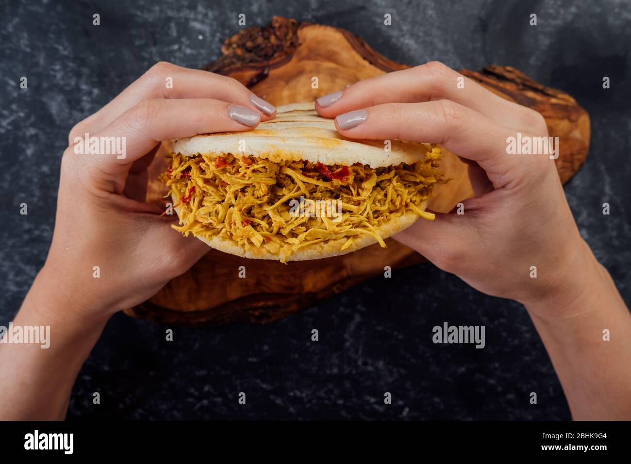 Woman holding a chicken arepa typical of Latin American cuisine. Stock Photo