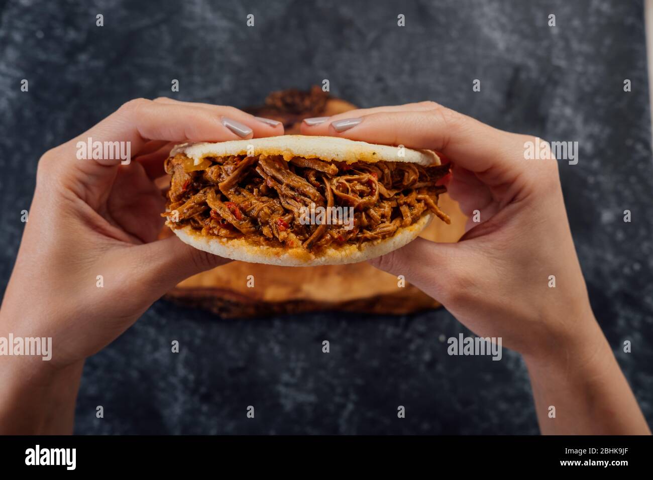Girl holding a meat Arepa, typical of Venezuelan cuisine. Stock Photo