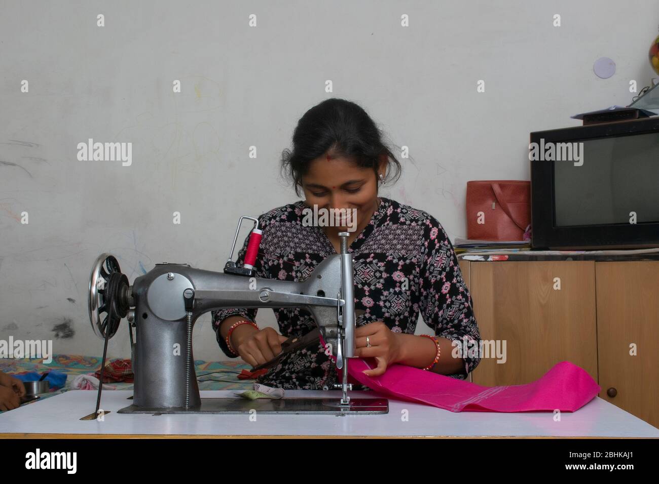 happy woman working on sewing machine as tailor 2BHKAJ1