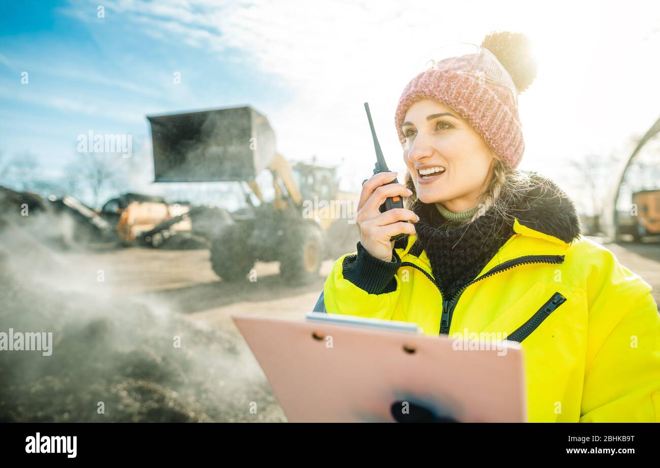 Manager in biomass and landfill operation using her radio in front of machines Stock Photo