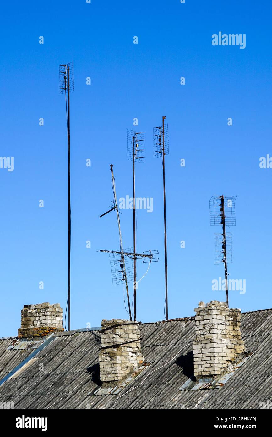 old analog television antennas of meter and decimeter ranges on the roof with three chimneys Stock Photo