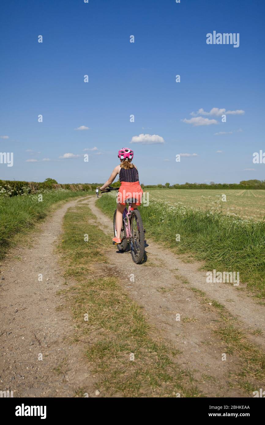 Young girls out for a bike ride on farm tacks, Oxfordshire, England Stock Photo