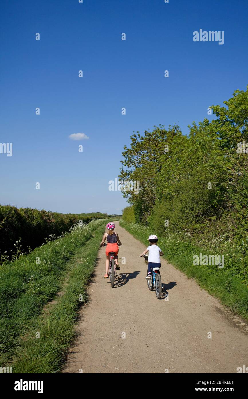 Young girls cycling up a dirt track, Oxfordshire, England Stock Photo