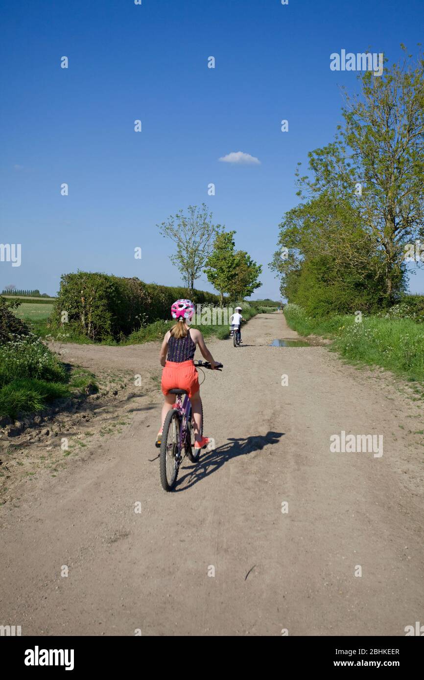 Young girls out for a cycle ride on a footpath, Oxfordshire, England Stock Photo