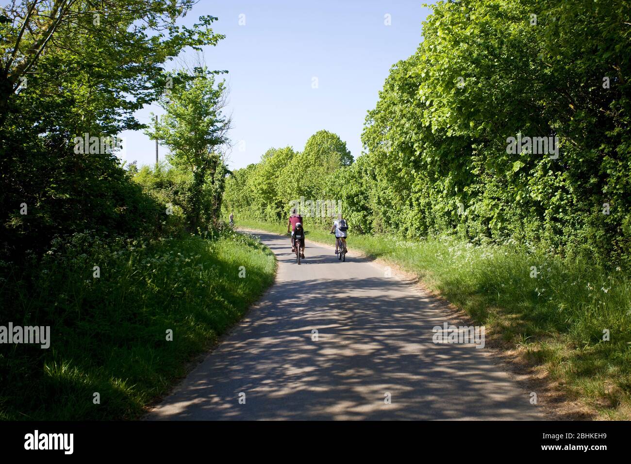 Young family cycling up empty lane Stock Photo