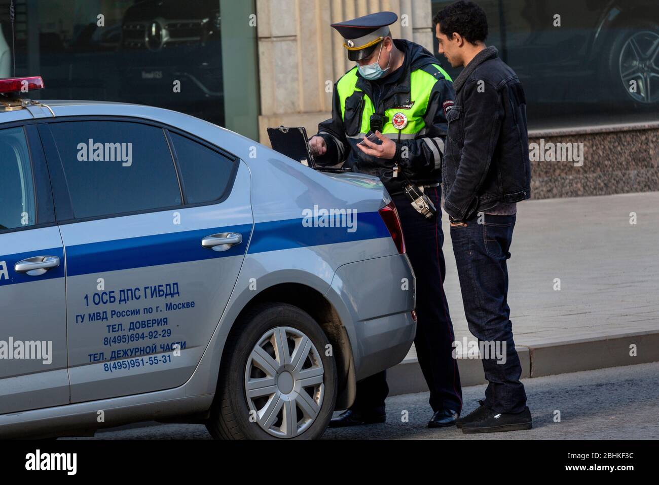Moscow, Russia. 26th of April, 2020. Traffic police officer in face masks checks a driver's digital pass code during the pandemic of the novel coronavirus disease COVID-19. On 13 April 2020, the Moscow government introduced a digital permit system aimed at further restricting movement. Under the new scheme, which has become mandatory from 15 April, people need to apply for permits to travel on a vehicle or public transport around the city Stock Photo