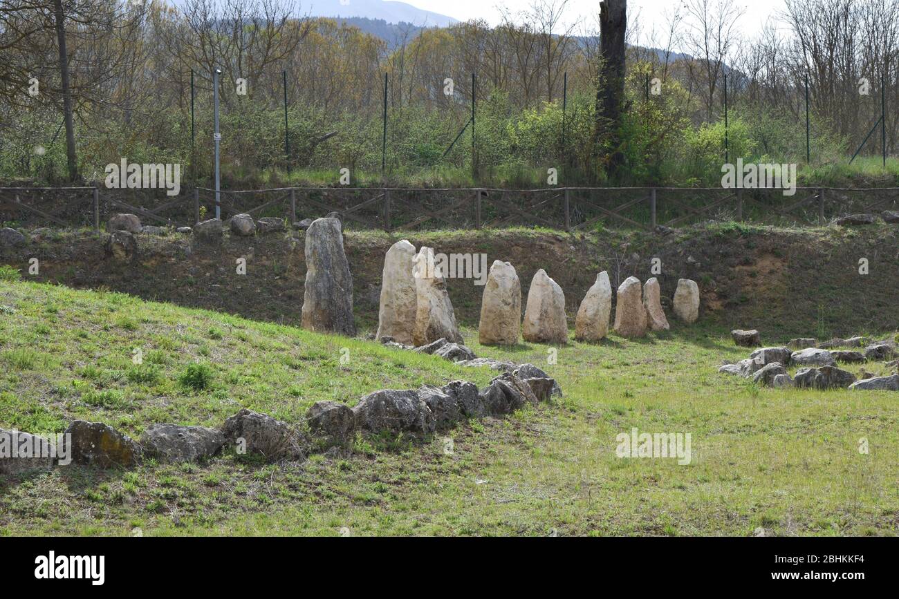  Large stone monoliths stand in a grassy field surrounded by a fence, part of an Iron Age necropolis in Amorosi, Italy.