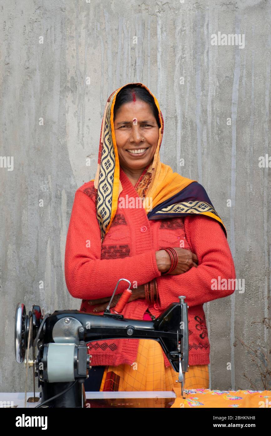 confident woman standing with sewing machine in rural India Stock Photo