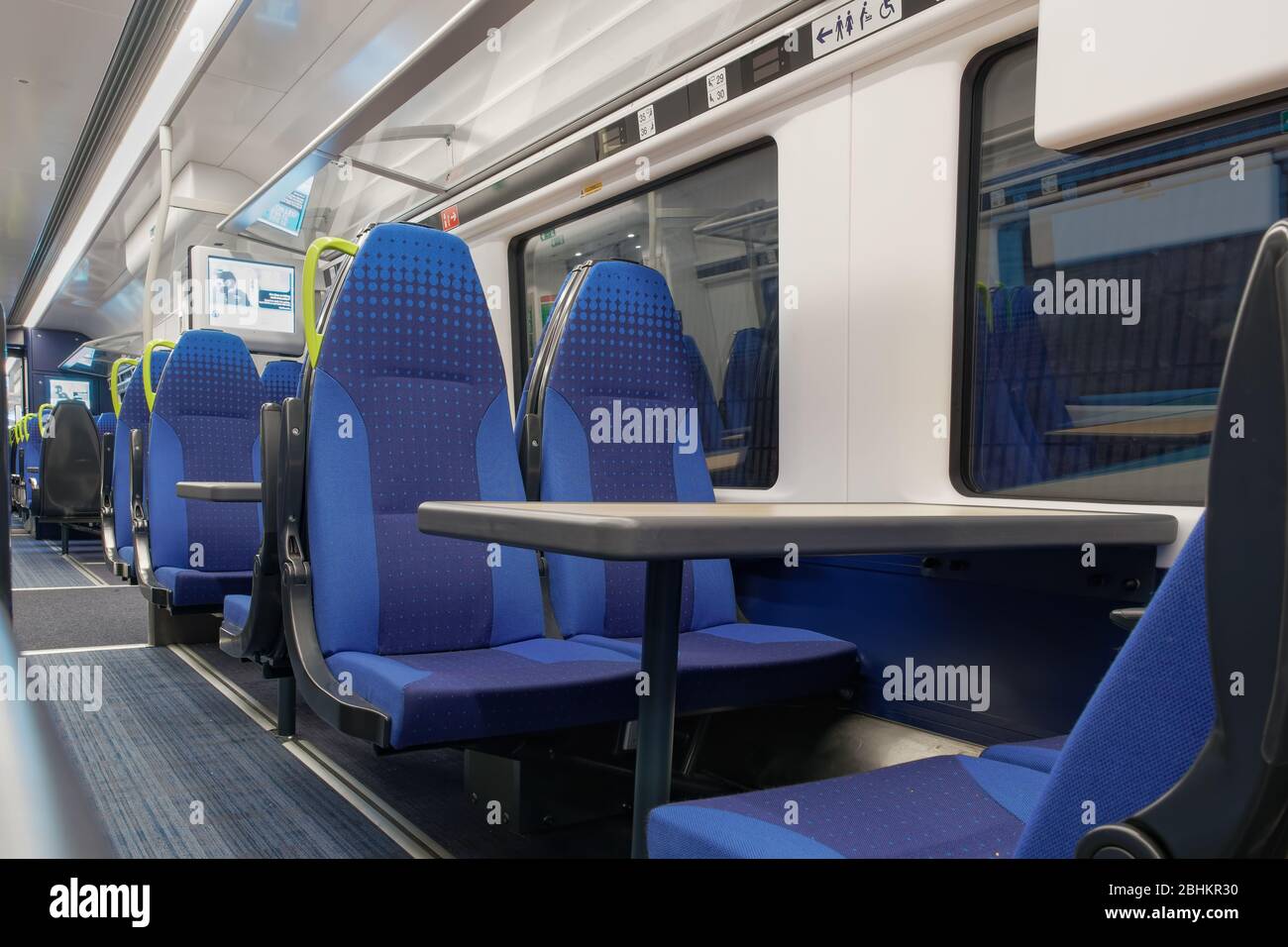 Interior of UK empty train stopped at station. Seat layout with tables and passenger lane inside Transpennine Express British train company coach. Stock Photo