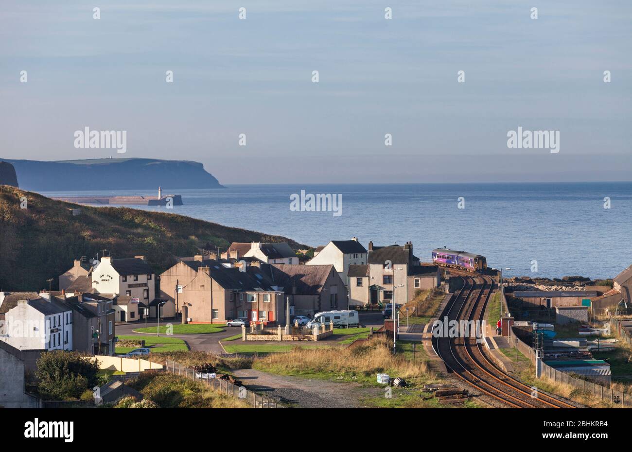 Northern rail class 156 sprinter train arriving at the village of Parton on the scenic  Cumbrian coast railway line with the Irish sea behind. Stock Photo
