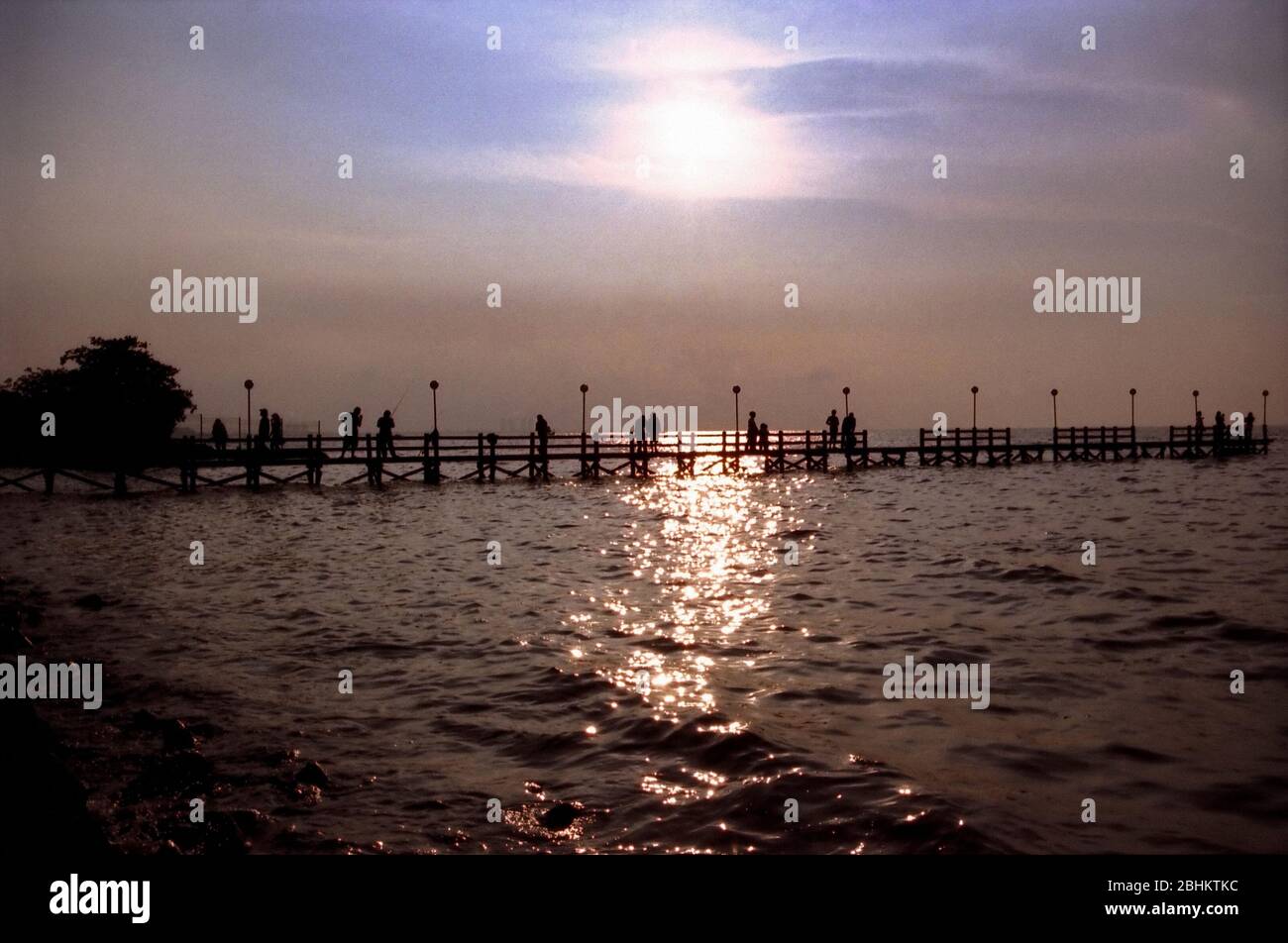 People enjoying afternoon view on wooden beach dock above sea level. Stock Photo