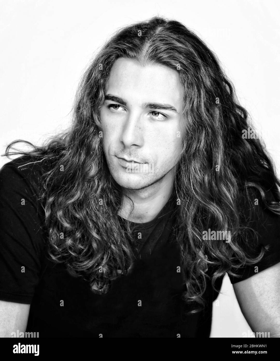 Stylish male model with long wavy hair posing in studio. Trends, style