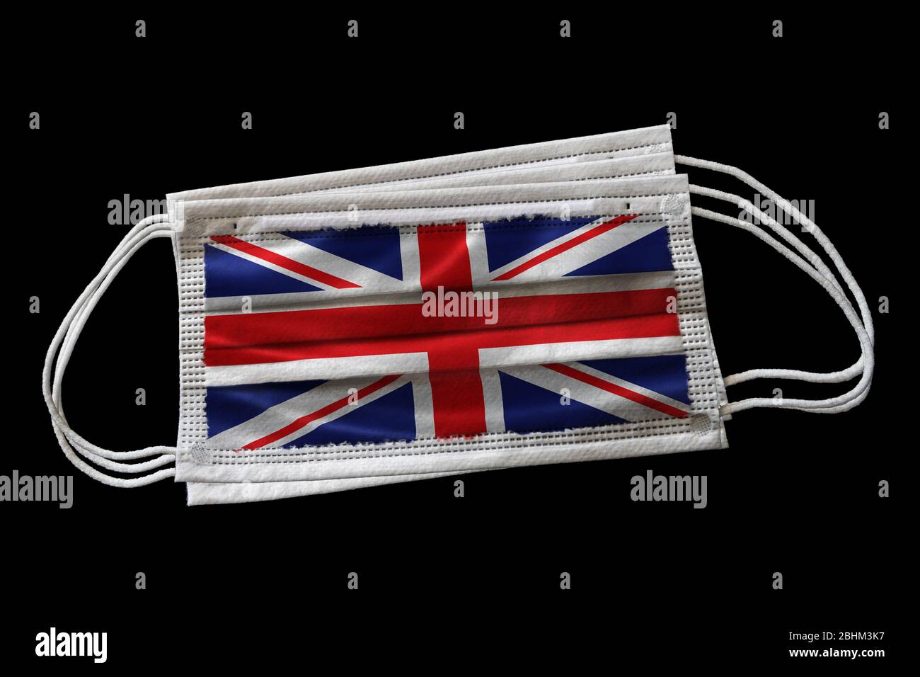 Multiple surgical face masks with UK flag printed. Isolated on black background. Concept of face mask usage in the British effort to combat Covid-19 c Stock Photo