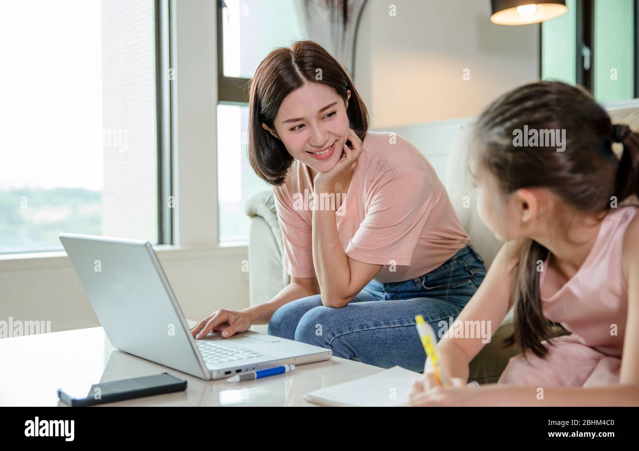 mother working at  home and help daughter doing home work Stock Photo