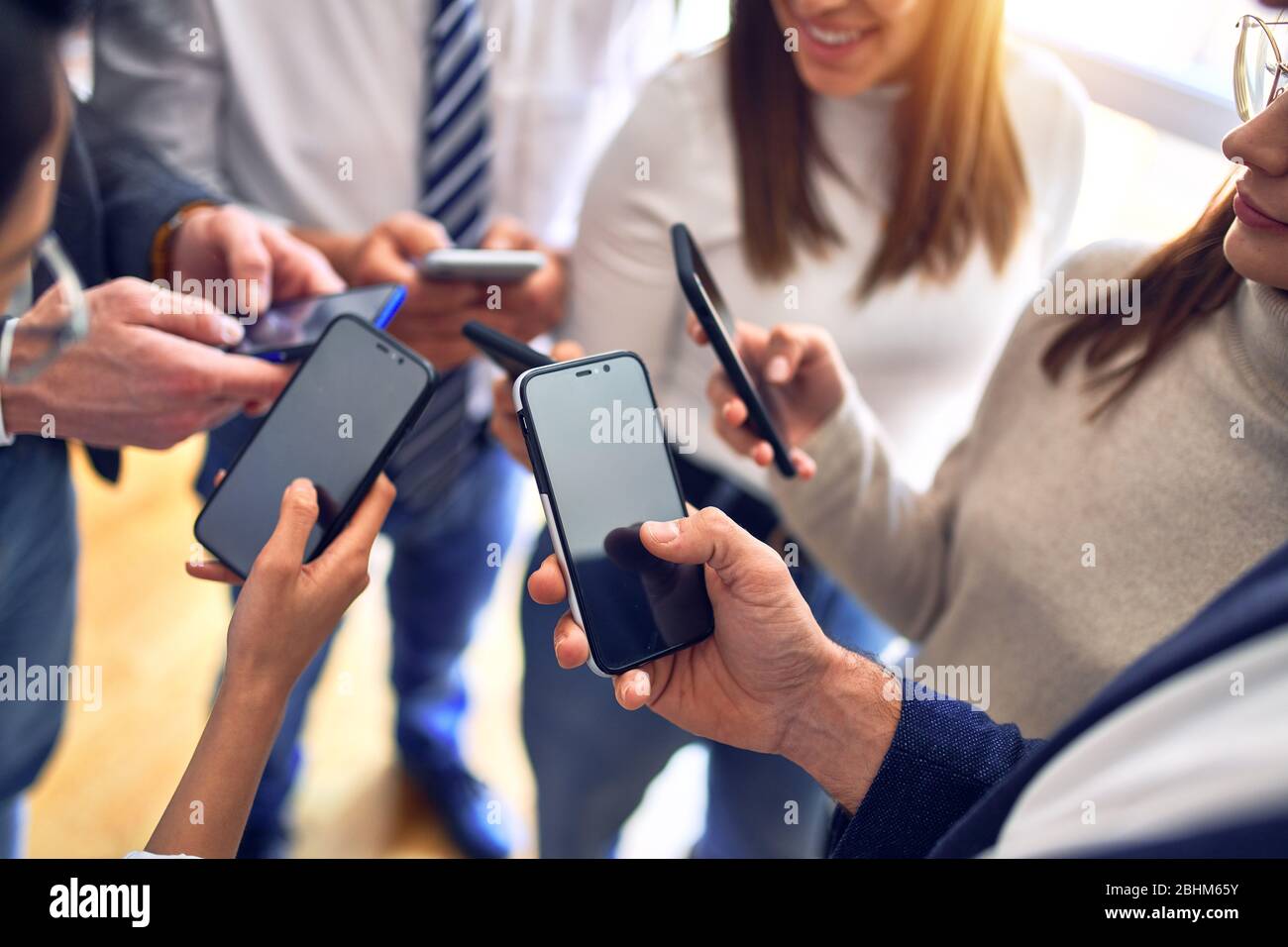 Worker Using Smartphone Group of business workers standing with hands together using smartphone ...