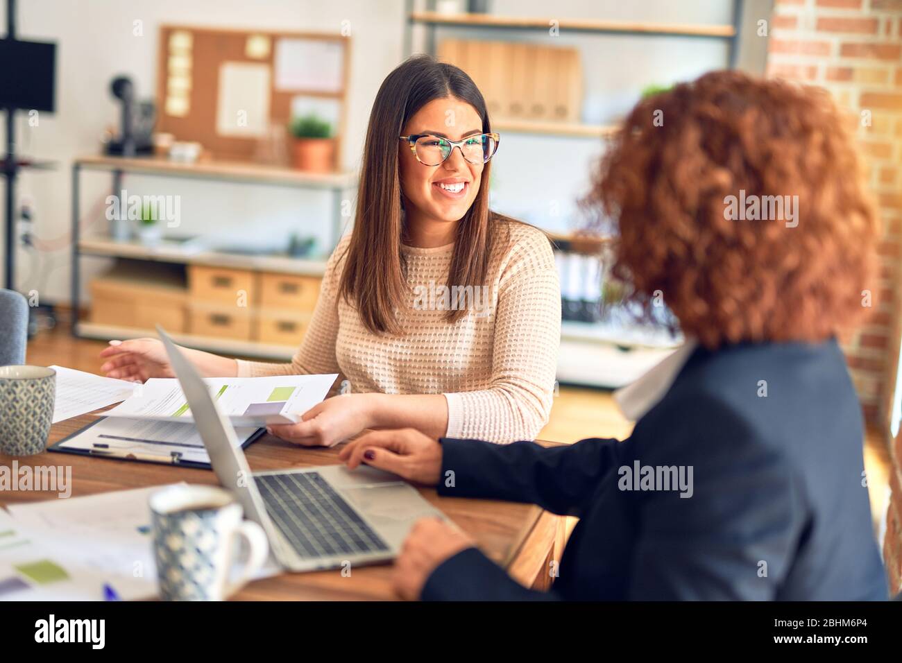Two beautiful businesswomen smiling happy and confident. Sitting with ...