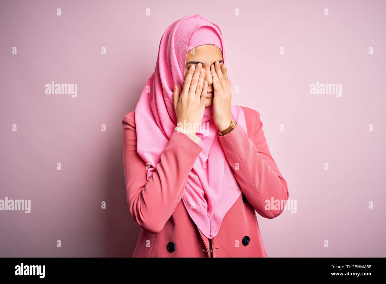 Young beautiful girl wearing muslim hijab standing over isolated pink background rubbing eyes for fatigue and headache, sleepy and tired expression. V Stock Photo