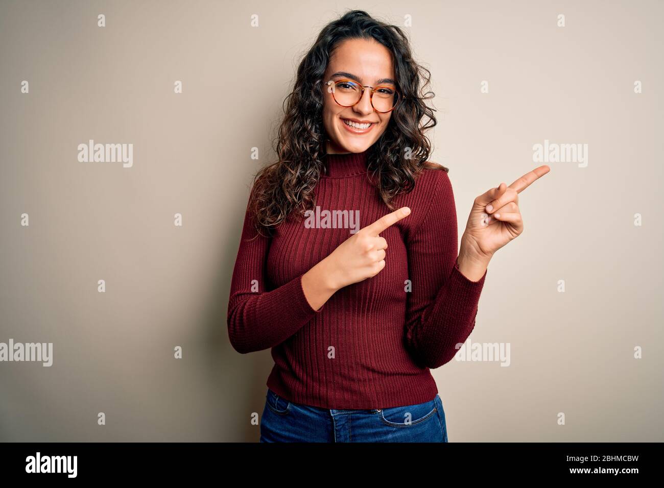 Beautiful woman with curly hair wearing casual sweater and glasses over ...