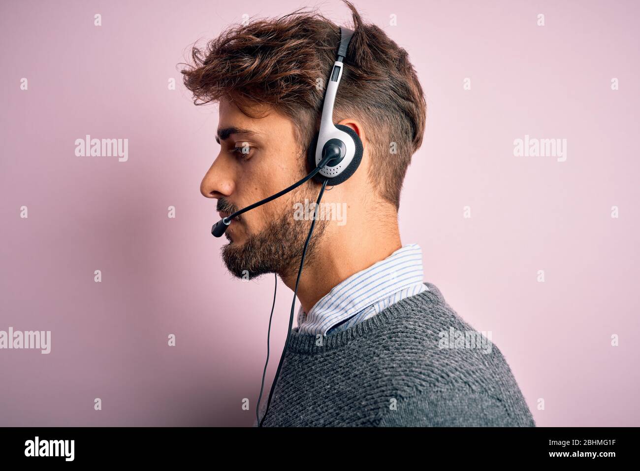 Young call center agent man with beard wearing headset over isolated pink  background looking to side, relax profile pose with natural face with  confid Stock Photo - Alamy