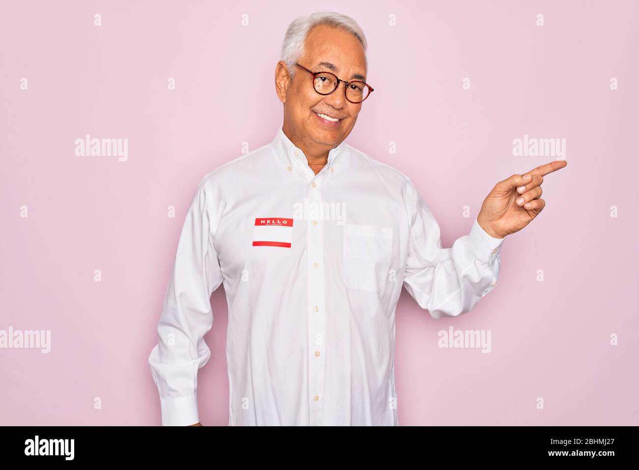 Middle age senior grey-haired man wearing hello my name is introduction ...