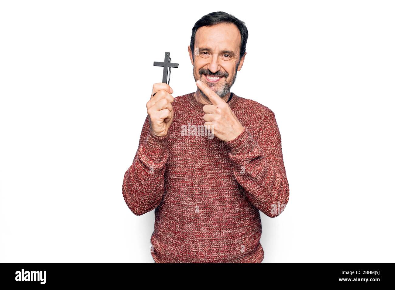 Middle age handsome catholic man praying holding christian cross over