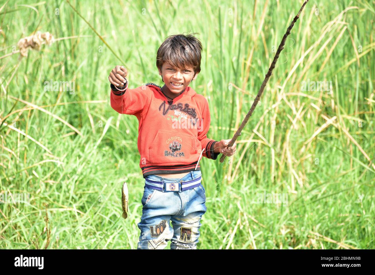 ndian boy fishing and showing fish with homemade rods in a lake in the Indian countryside. Stock Photo