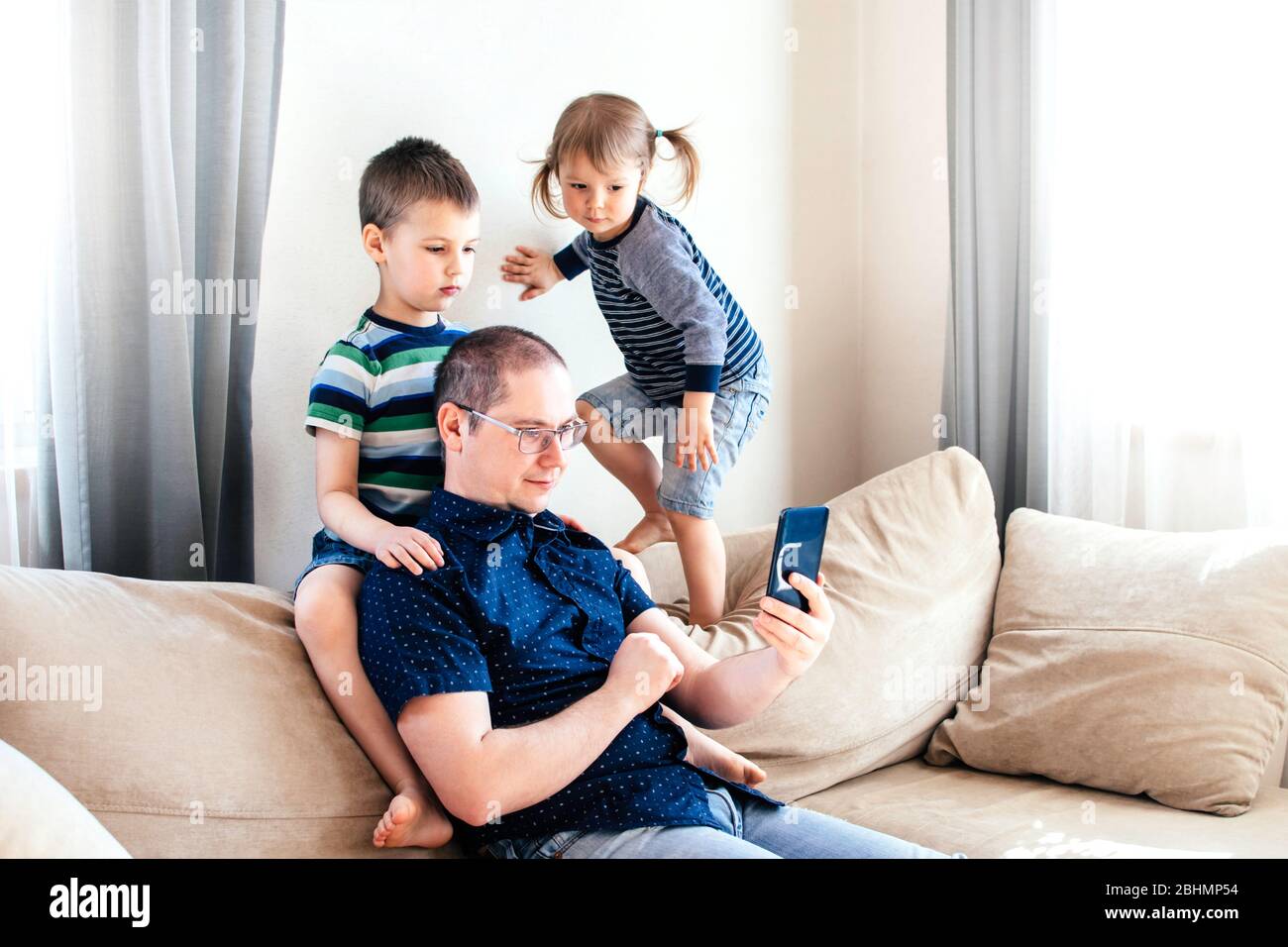 Father and his children talking online by phone with relatives or friends. Online communication. Family in quarantine stay at home in self isolation. Stock Photo