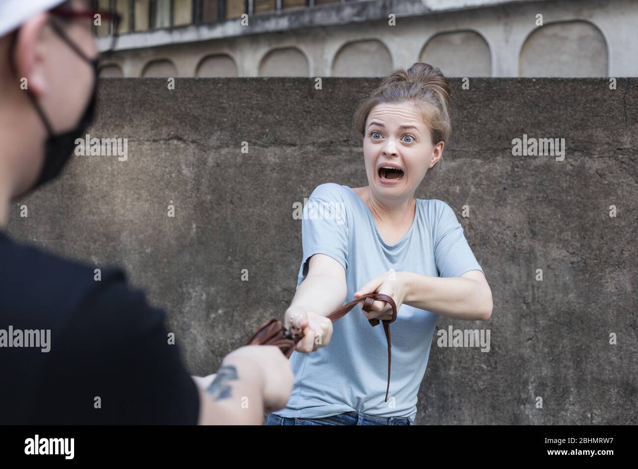Scared young Caucasian woman is mugged robbed by masked man. Street robbery  attack concept Stock Photo - Alamy