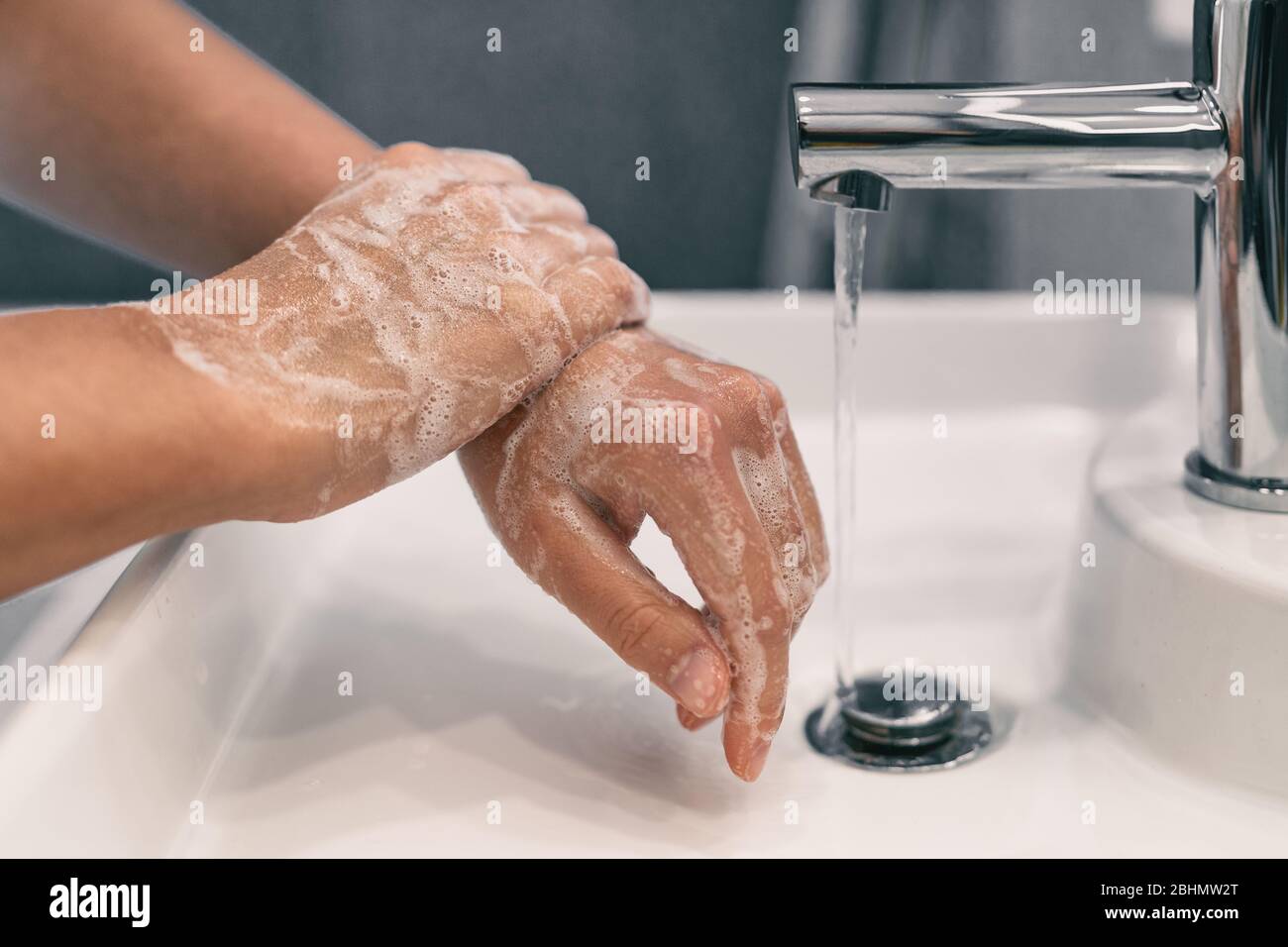 Hand washing personal hygiene woman washing hands rubbing soap for 20 seconds following steps, cleaning wrists and rinsing under water at home bathroom. COVID-19 infection prevention handwashing. Stock Photo
