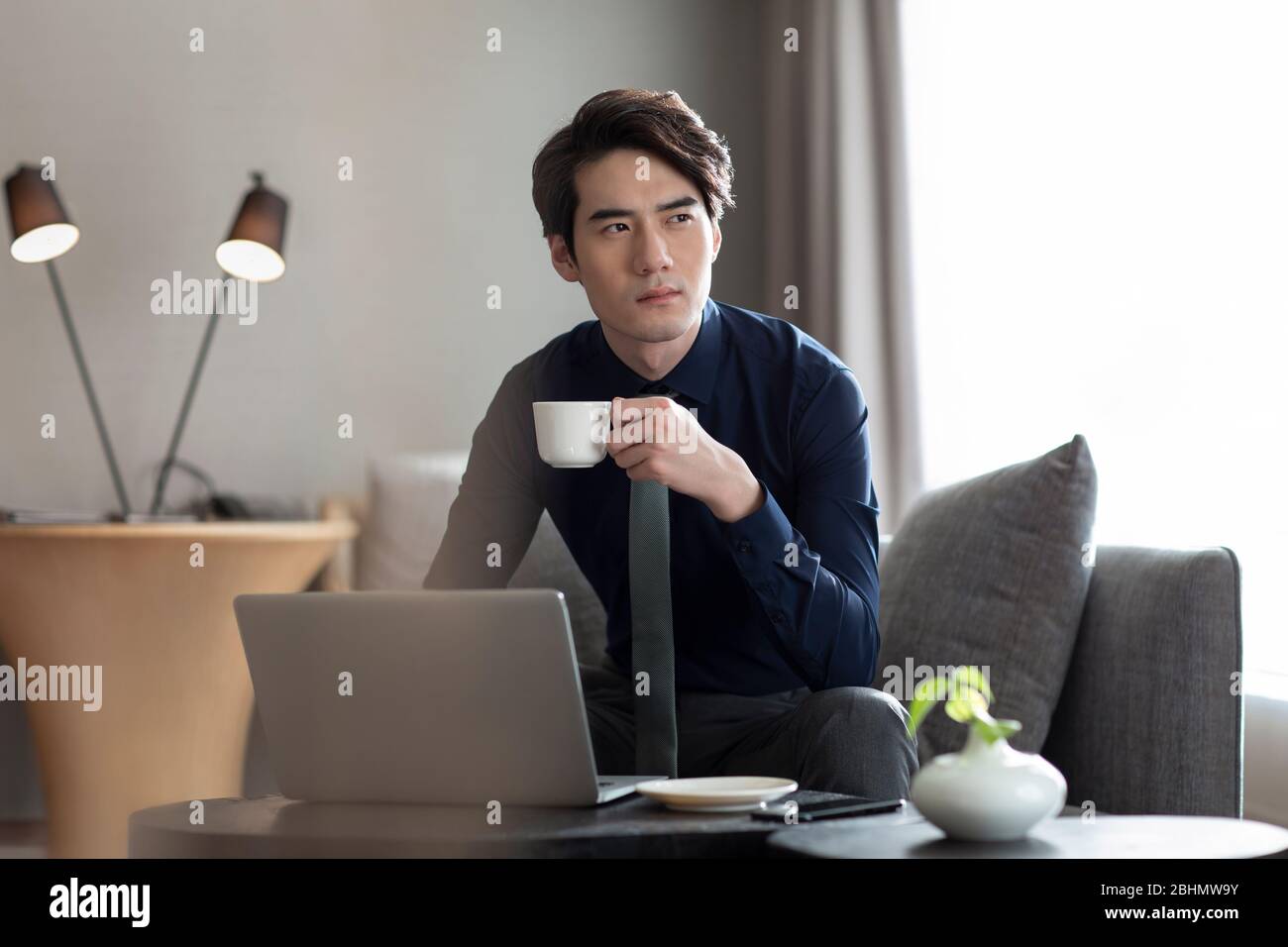 Young Chinese businessman drinking coffee in hotel room Stock Photo Alamy