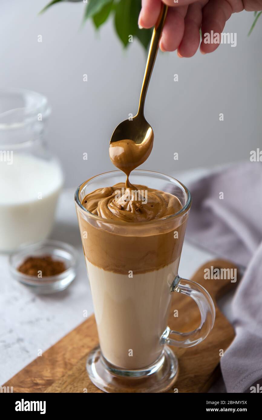 Spreading foam on a dalgon coffee spoon. Korean drink in a tall glass with whipped coffee Stock Photo