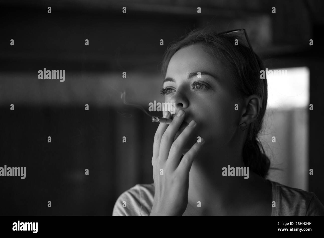 Black and white portrait of young caucasian woman girl smoking a cigarette, looking depressed or sad Stock Photo