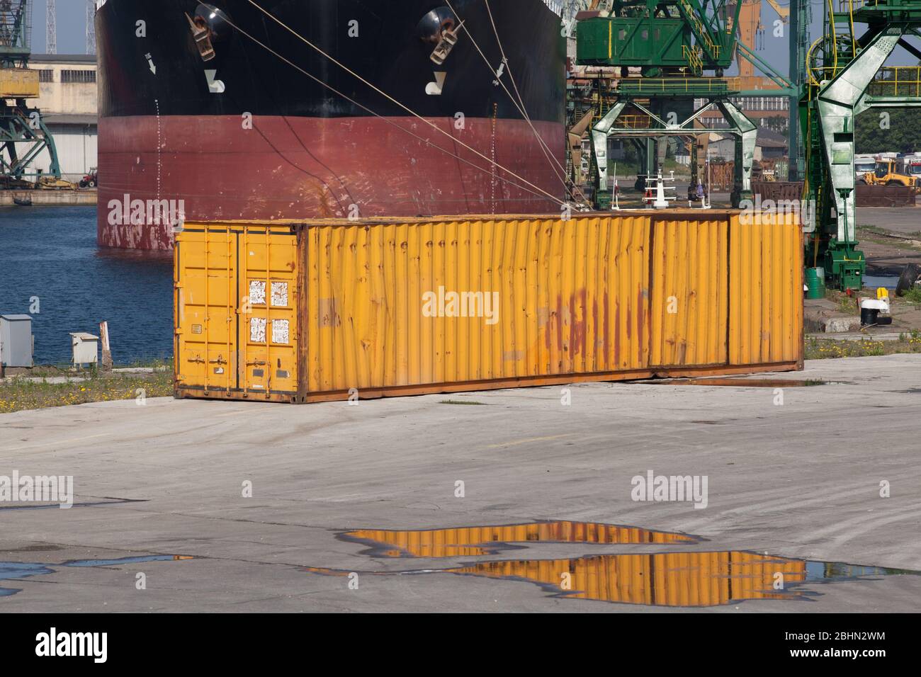 Grungy yellow old cargo container stands in a harbor district, industrial shipping equipment Stock Photo