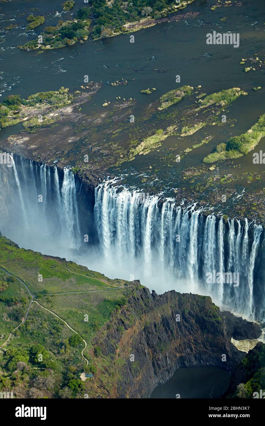 Victoria Falls or "Mosi-oa-Tunya" (The Smoke that Thunders), and Zambezi River, Zimbabwe / Zambia border, Southern Africa - aerial Stock Photo