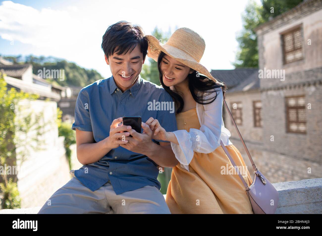 Happy young Chinese couple using smartphone outdoors Stock Photo