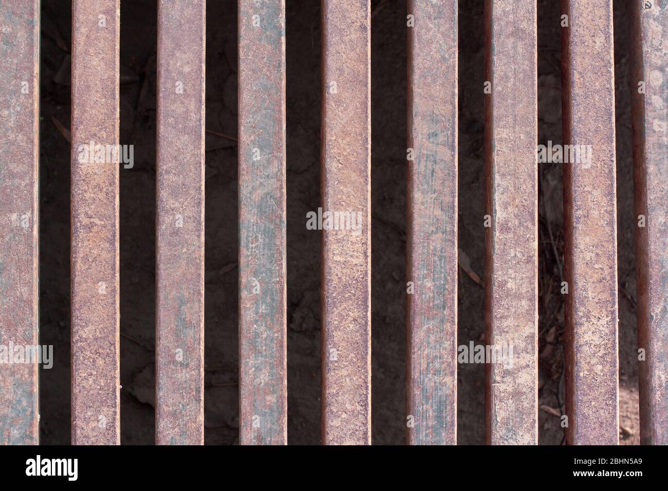 Iron grate over the drainage channel on the road. Rusty texture and scuffs on the metal. Horizontal. Stock Photo