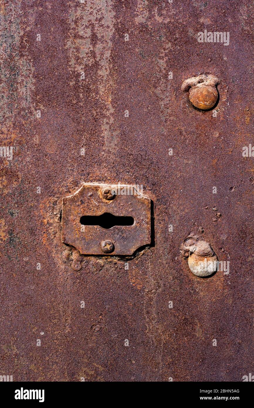 Grunge texture of an old rusty keyhole in a garage door. Two large