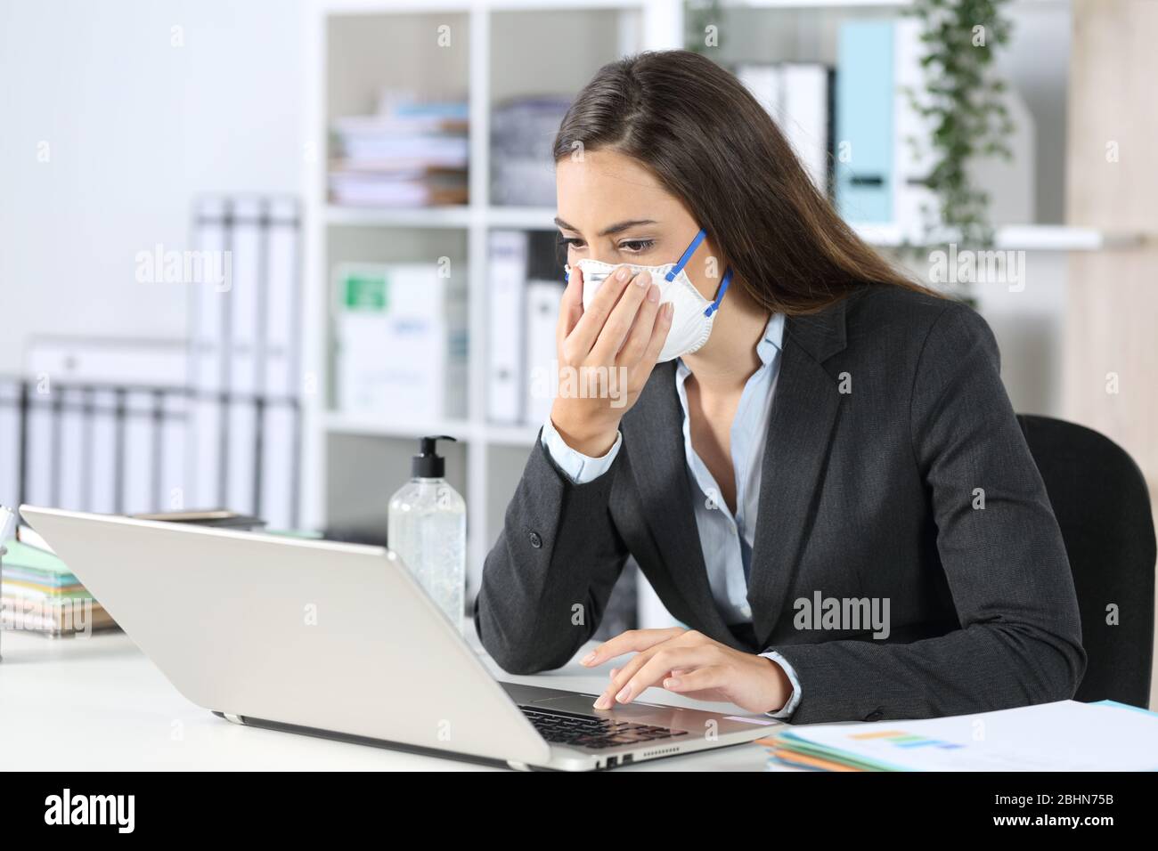 Executive exposing herself to contagion touching protective mask working at office Stock Photo