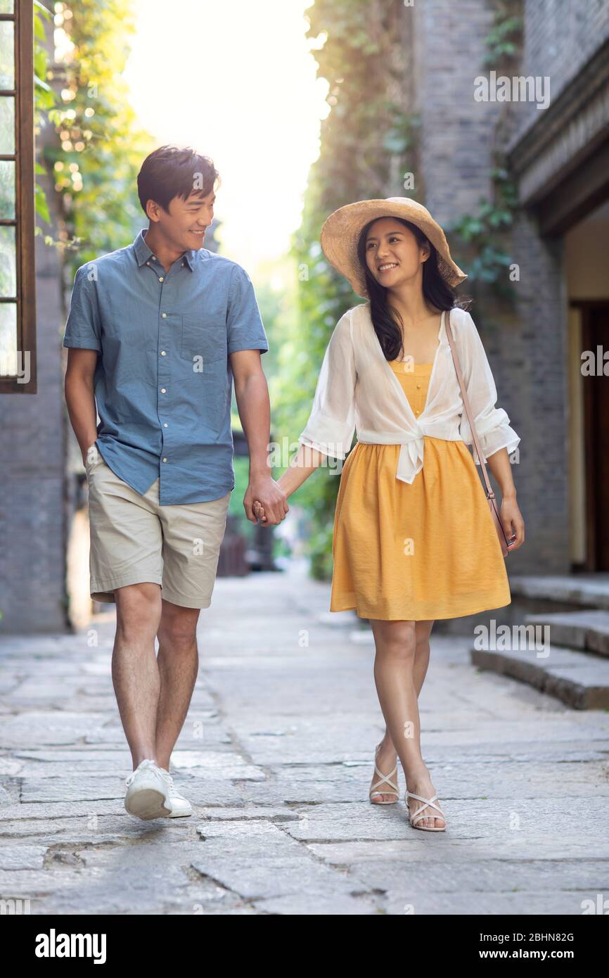 Happy young Chinese couple walking in alley Stock Photo - Alamy