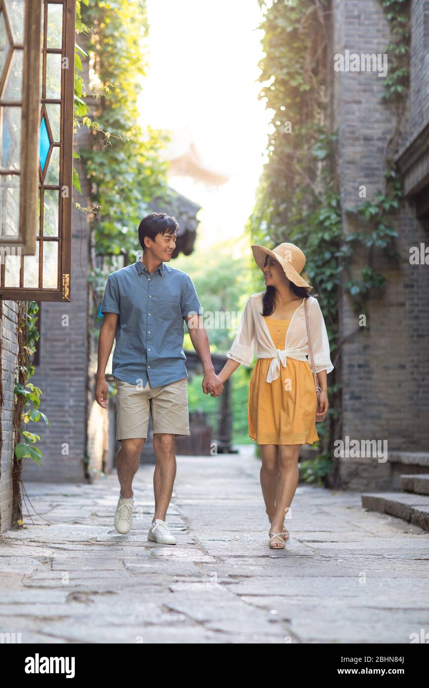 Happy young Chinese couple walking in alley Stock Photo - Alamy