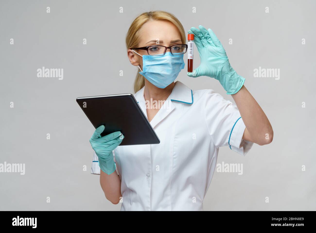 medical doctor nurse woman wearing protective mask and gloves - holding virus blood test and tablet pc Stock Photo
