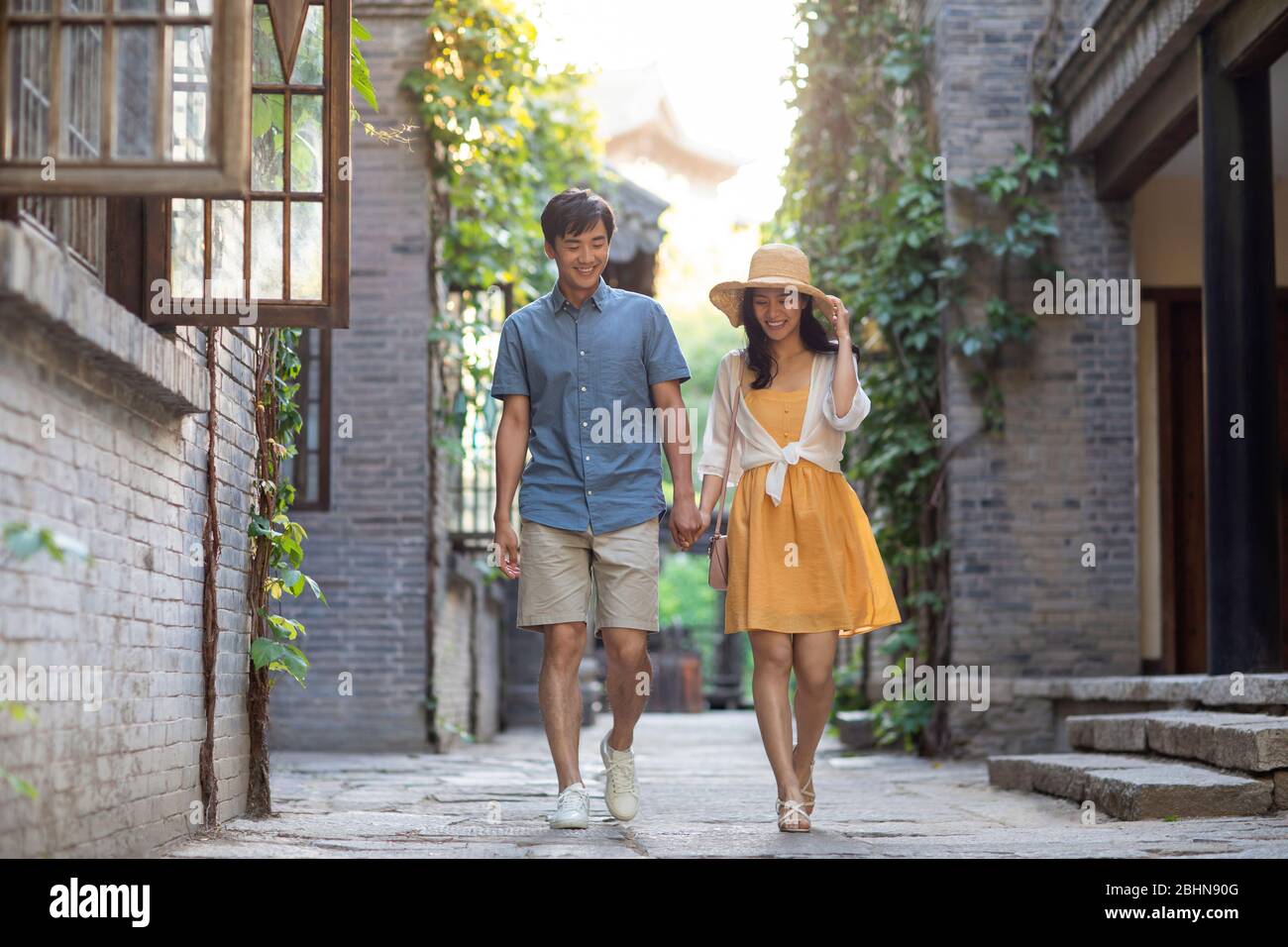 Happy young Chinese couple walking in alley Stock Photo - Alamy