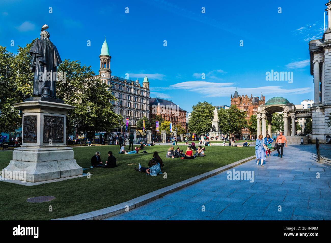Park with many people lying on the meadows in front of City Hall in Belfast, United Kingdom. Belfast is the capital of northern Ireland. Stock Photo